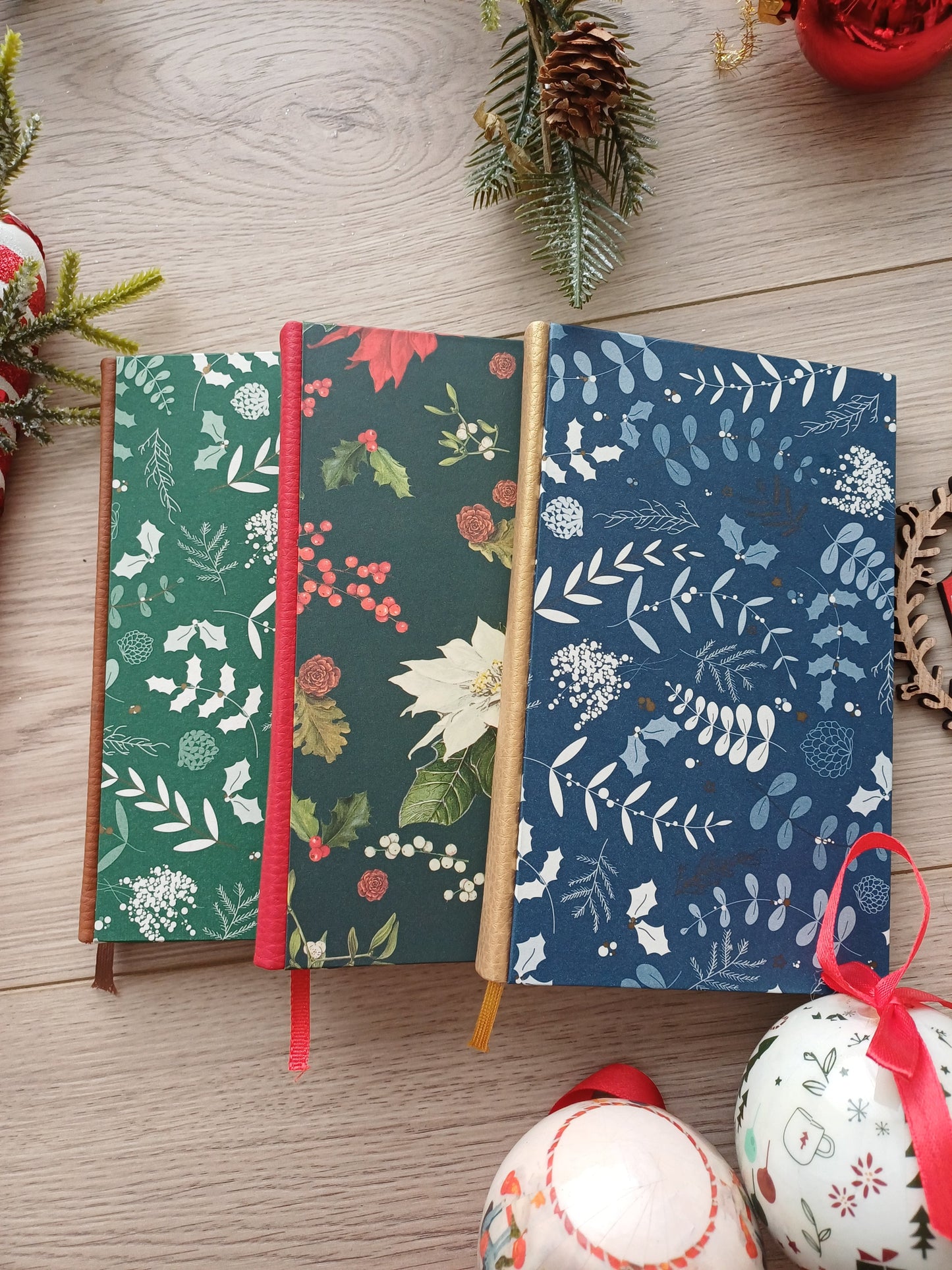 Trois carnets aux couvertures évoquant Noël entourés de décorations