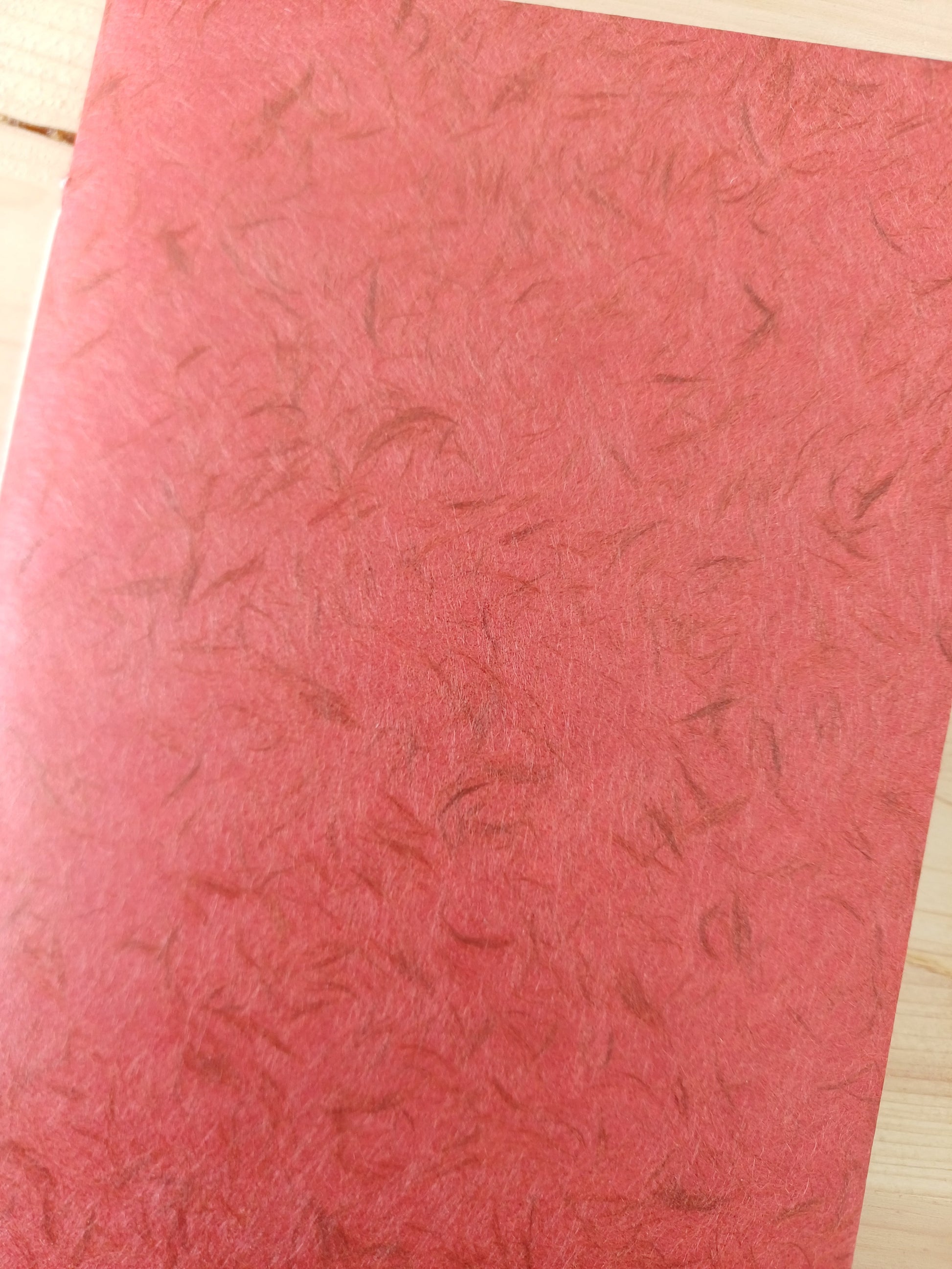 Petit carnet artisanal à la couverture de papier japonais obonai de couleur terracotta.