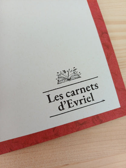 Détail de la page de garde d'un carnet artisanal avec un tampon de la marque les carnets d'Evriel. Les rebords montrent une couverture de papier japonais obonai couleur terracota.