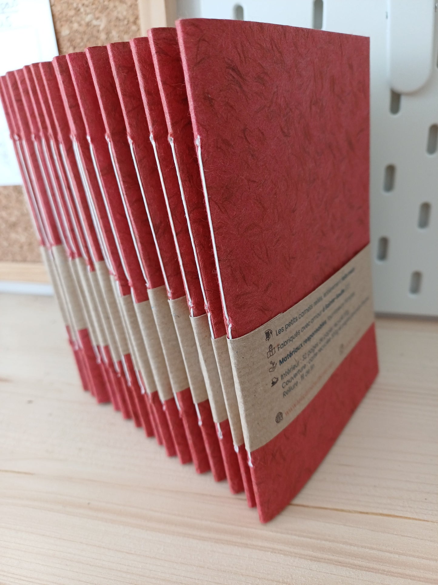 Quinze carnets artisanaux reliés à la main recouverts d'un papier japonais obonai tarracota et d'un beandeau de papier kraft
