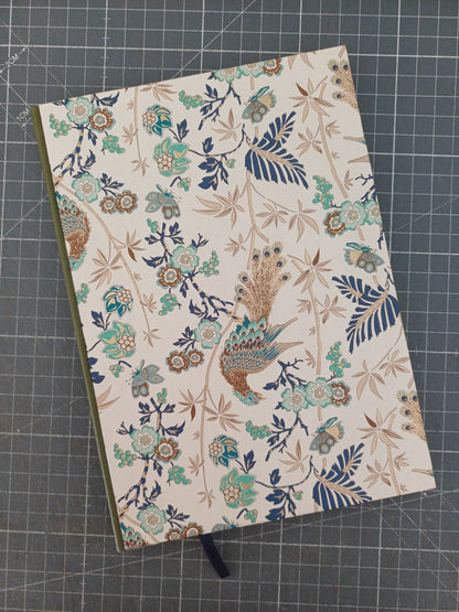 Carnet artisanal à la couverture imprimée de paons et de végétation aux reflets dorés avec un dos en similicuir vert.