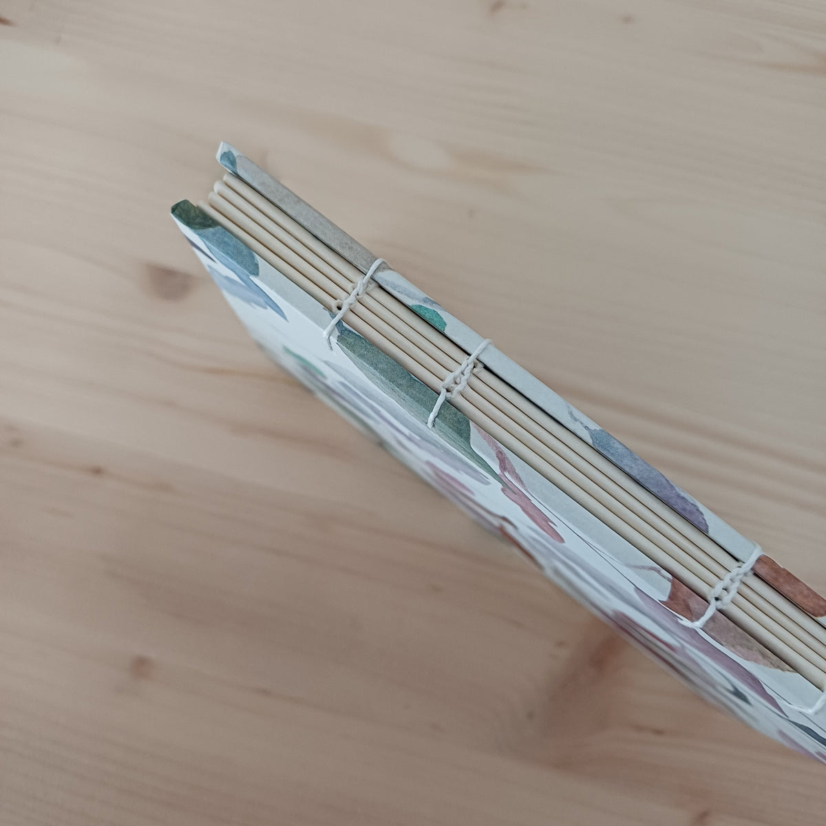 Carnet artisanal relié dont on voit le dos avec la reliure copte apparente. 