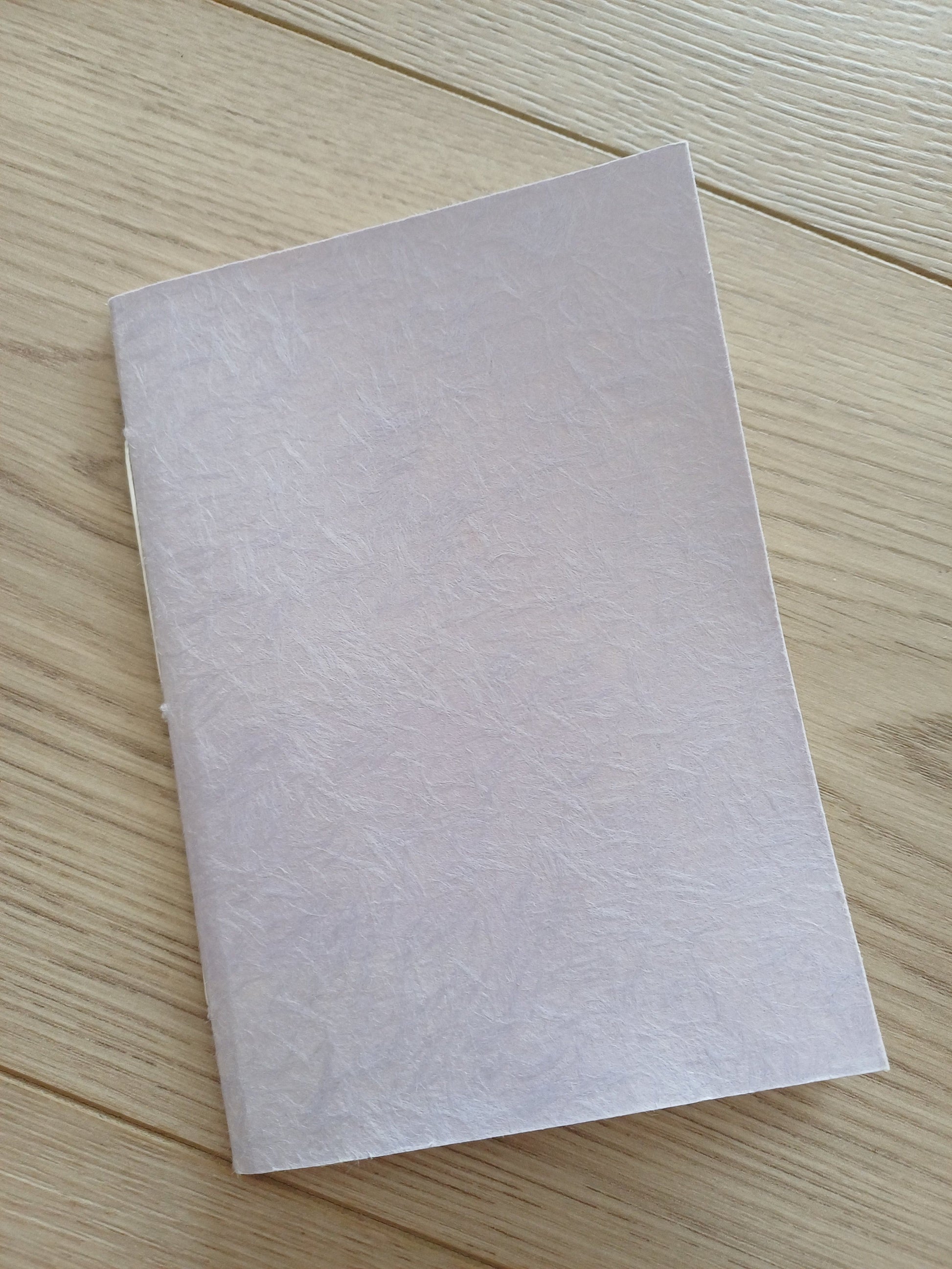 Petit carnet artisanal relié à la main à la couverture de papier japonais obonai lilas.