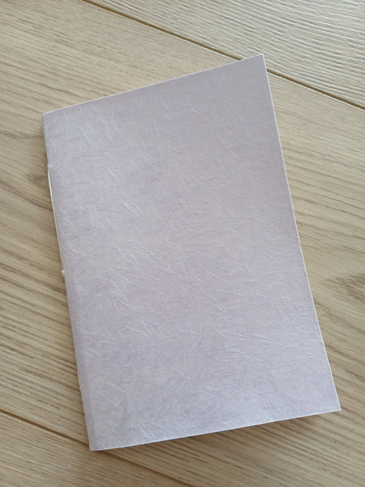 Petit carnet artisanal relié à la main à la couverture de papier japonais obonai lilas.