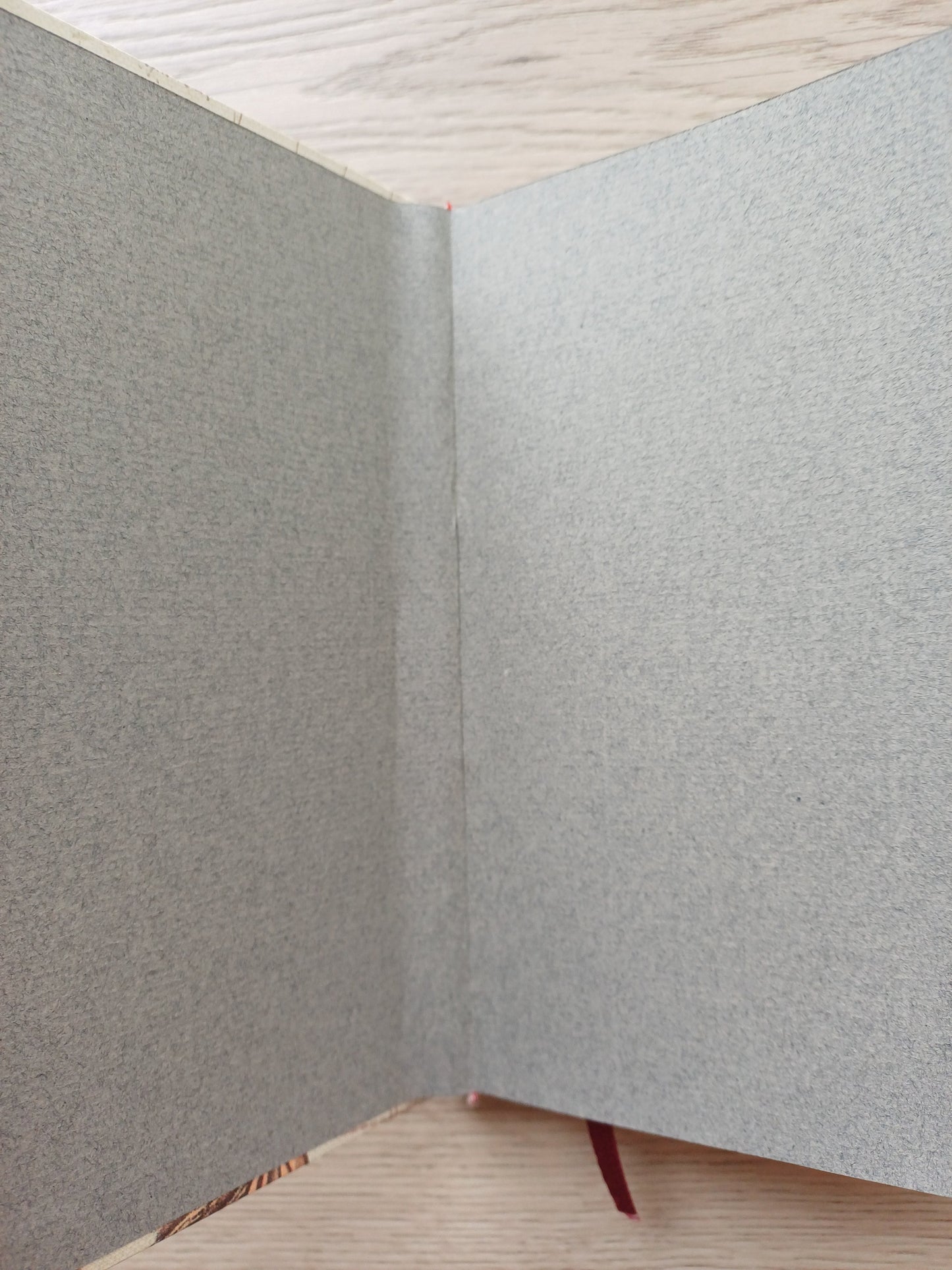 Carnet artisanal ouvert sur les pages de garde dont on voit un défaut de collage.