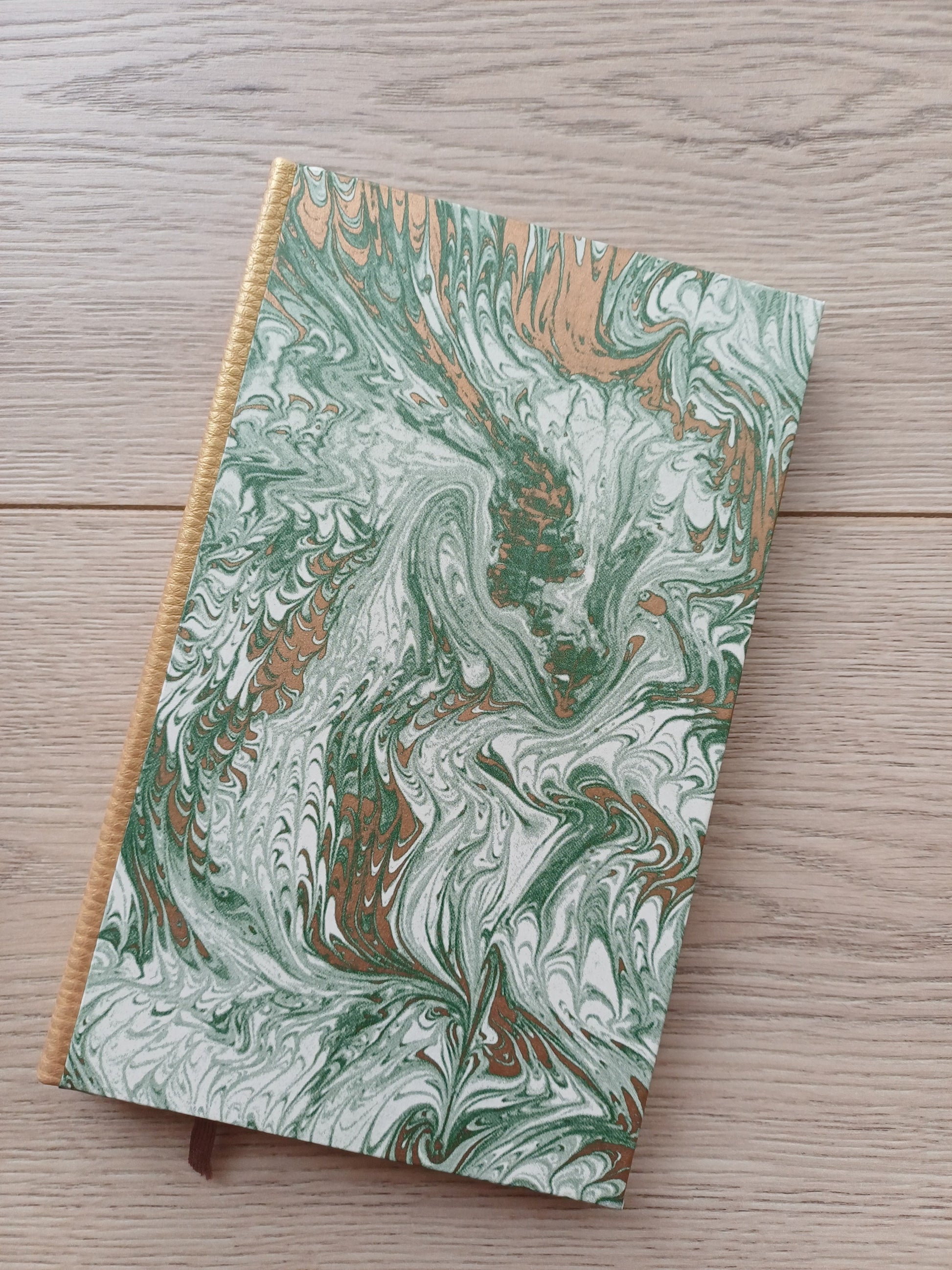 Carnet artisanal avec une couverture imprimée d'un motif marbré vert et doré.