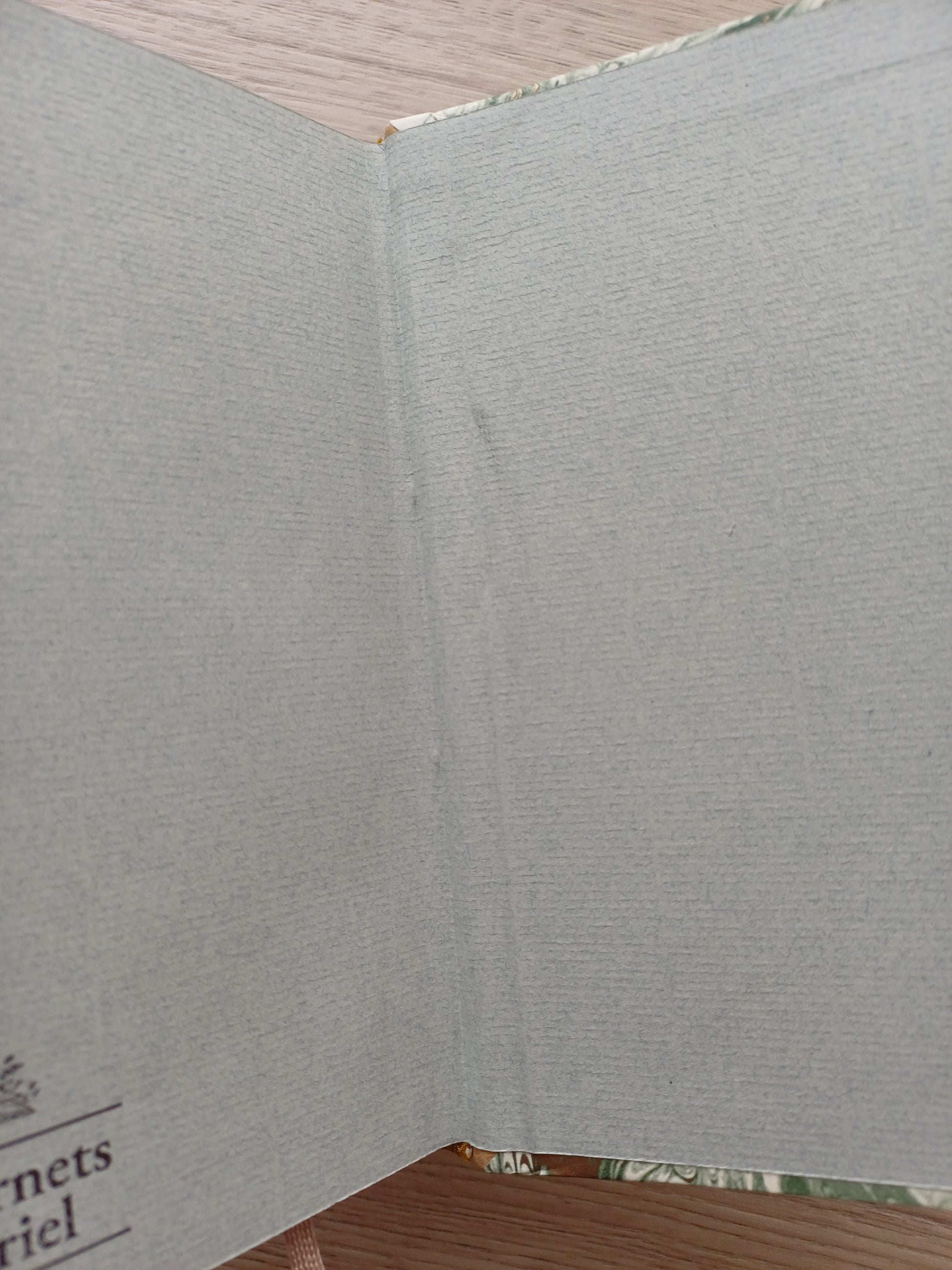 Carnet ouvert sur une page de garde dont on voit un défaut de collage.