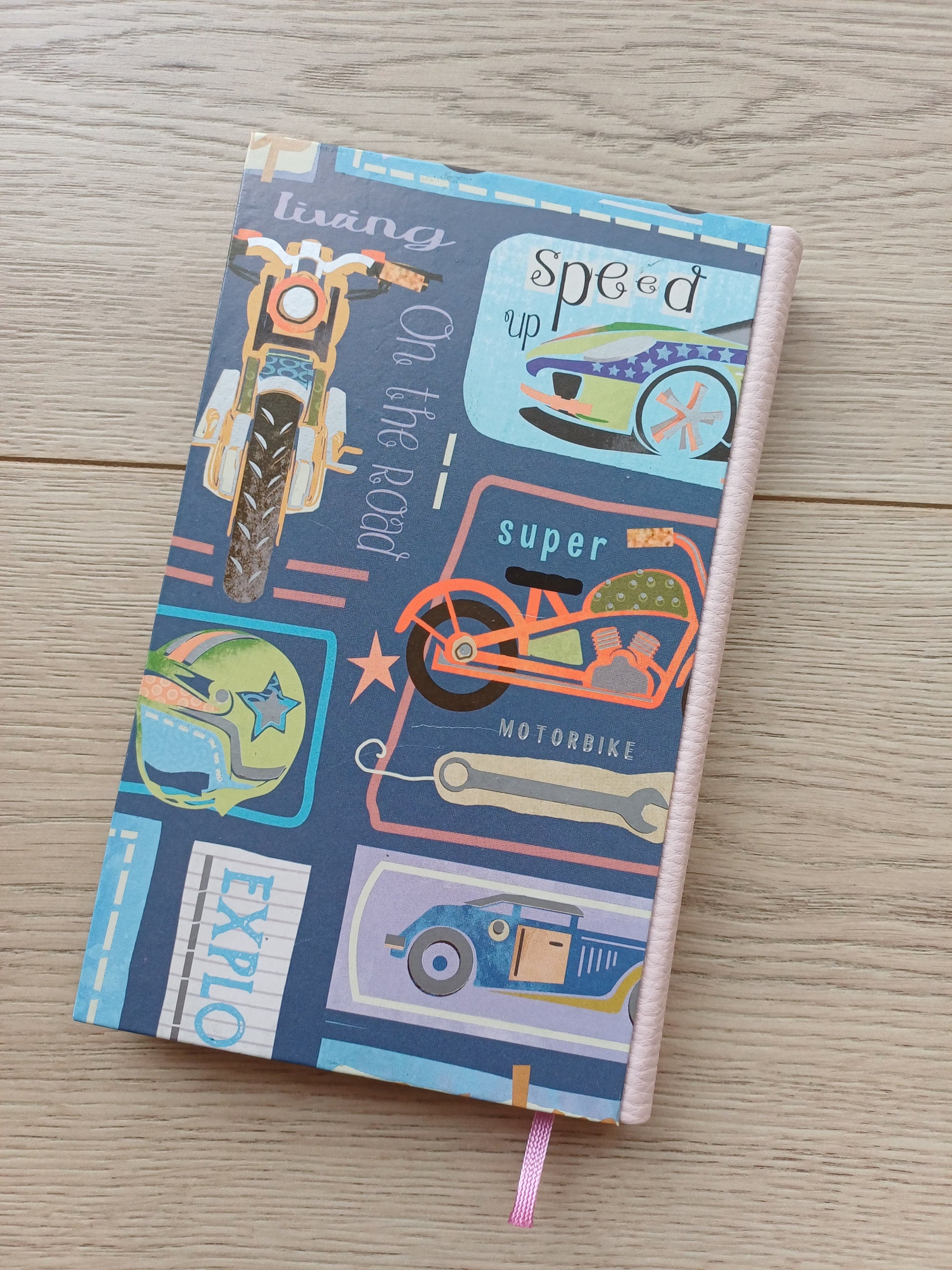 Carnet artisanal avec une couverture imprimée de dessins évoquant les roads trips et la route 66 : des voitures, des motos, des panneaux...