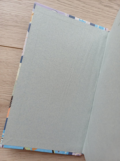 Carnet artisanal ouvert sur les pages de garde dont on voit un défaut de collage.