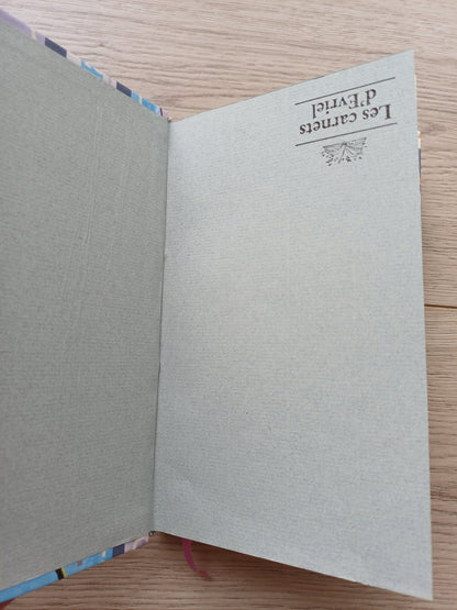 Carnet artisanal ouvert sur sa page de garde dont on voit un défaut de collage et le tampon de la marque mis à l'envers.