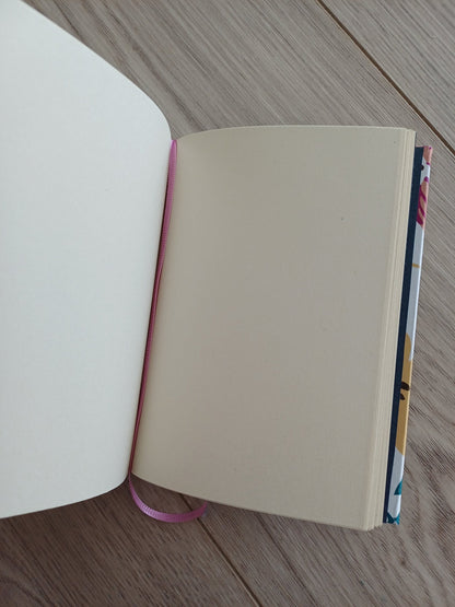 Carnet artisanal ouvert, on voit le signet rose et un bout de couverture au papier imprimé fleuri.