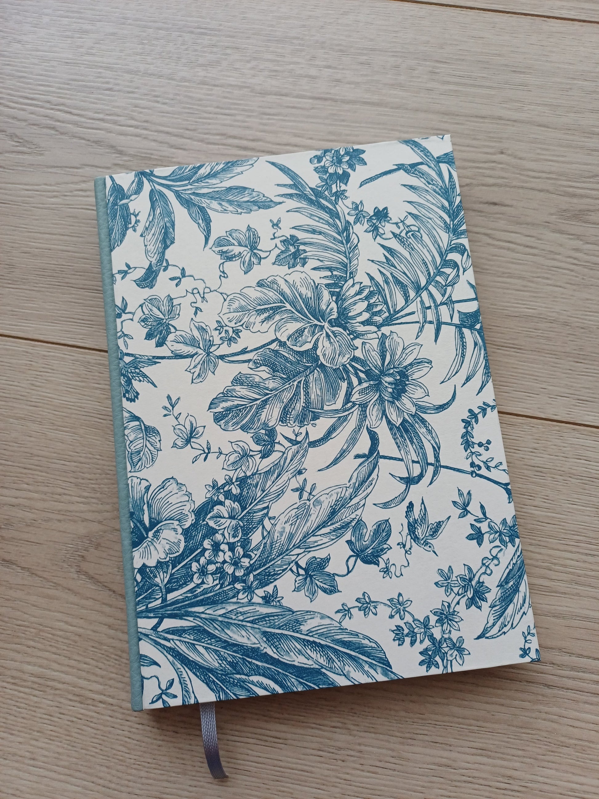 Carnet artisanal à la couverture imprimée de fleurs et feuillages bleus.