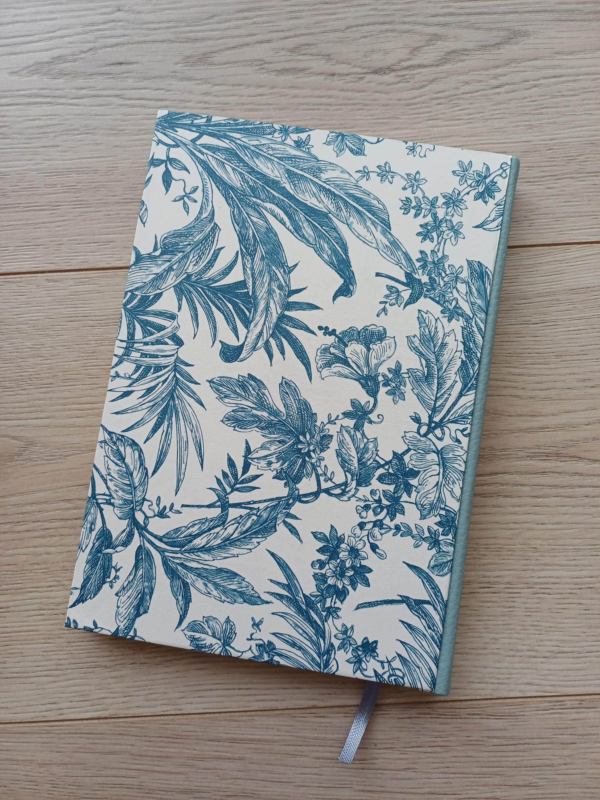 Carnet artisanal à la couverture imprimée de fleurs et feuillages bleus.