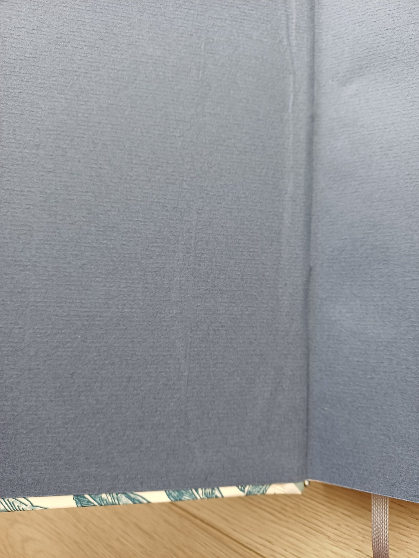 Carnet artisanal ouvert sur sa page de garde dont on voit un défaut de collage.