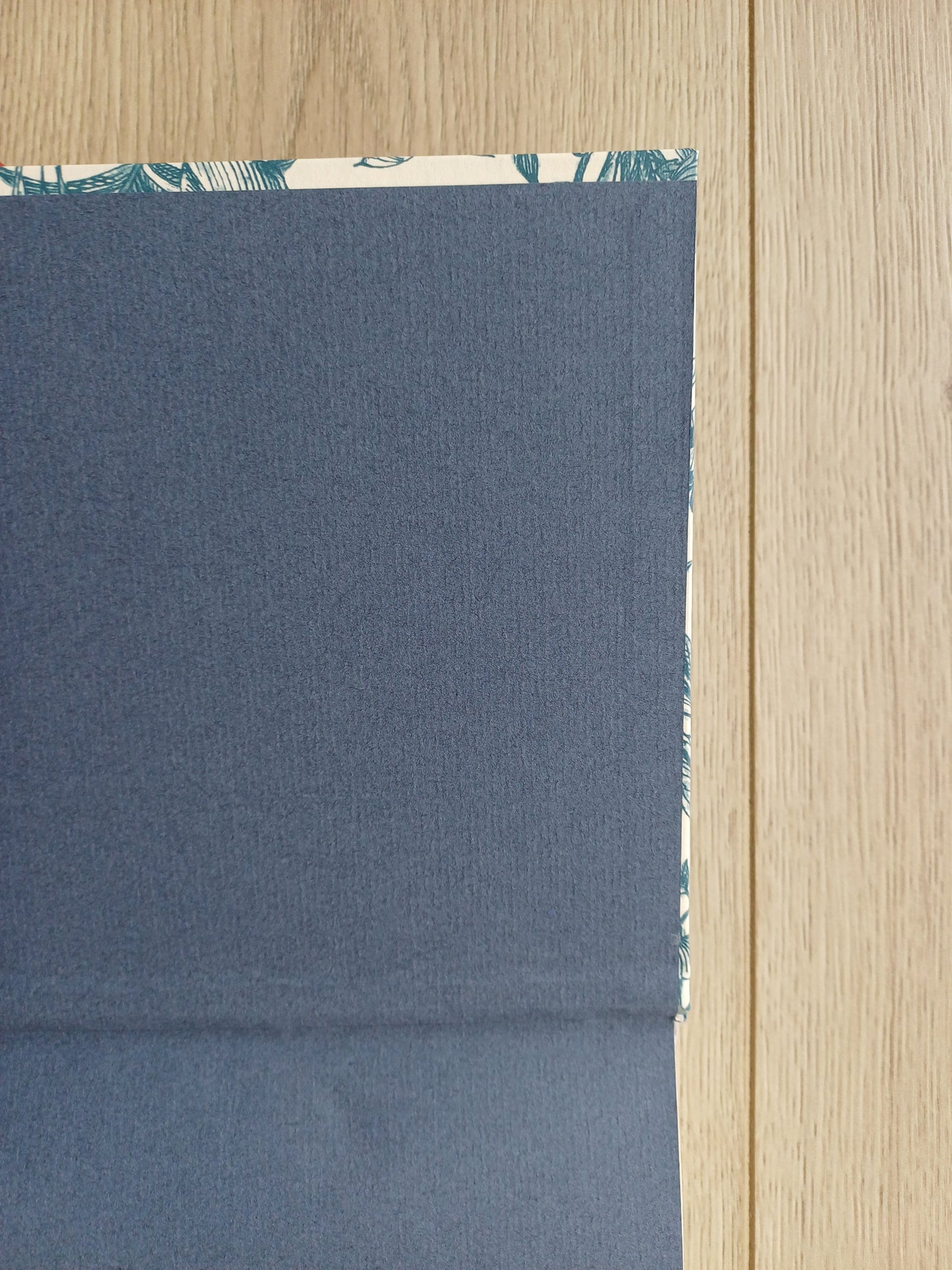 Carnet artisanal ouvert sur les pages de gardes qui sont collées légèrement de travers juste au bord de la couverture.