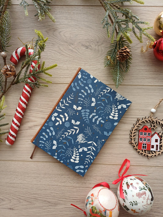 Carnet aux décorations de Noël sur fond bleu entouré de décorations de Noël