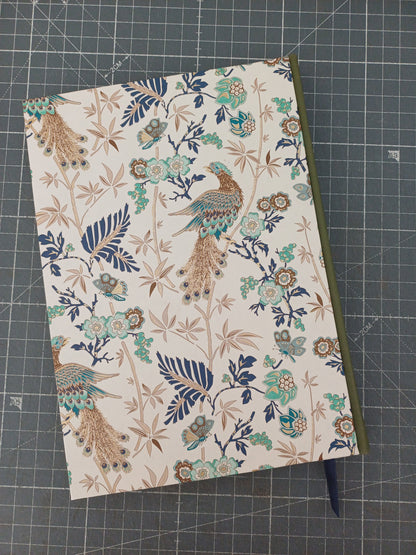 Carnet artisanal à la couverture imprimée de paons et de végétation aux reflets dorés avec un dos en similicuir vert.