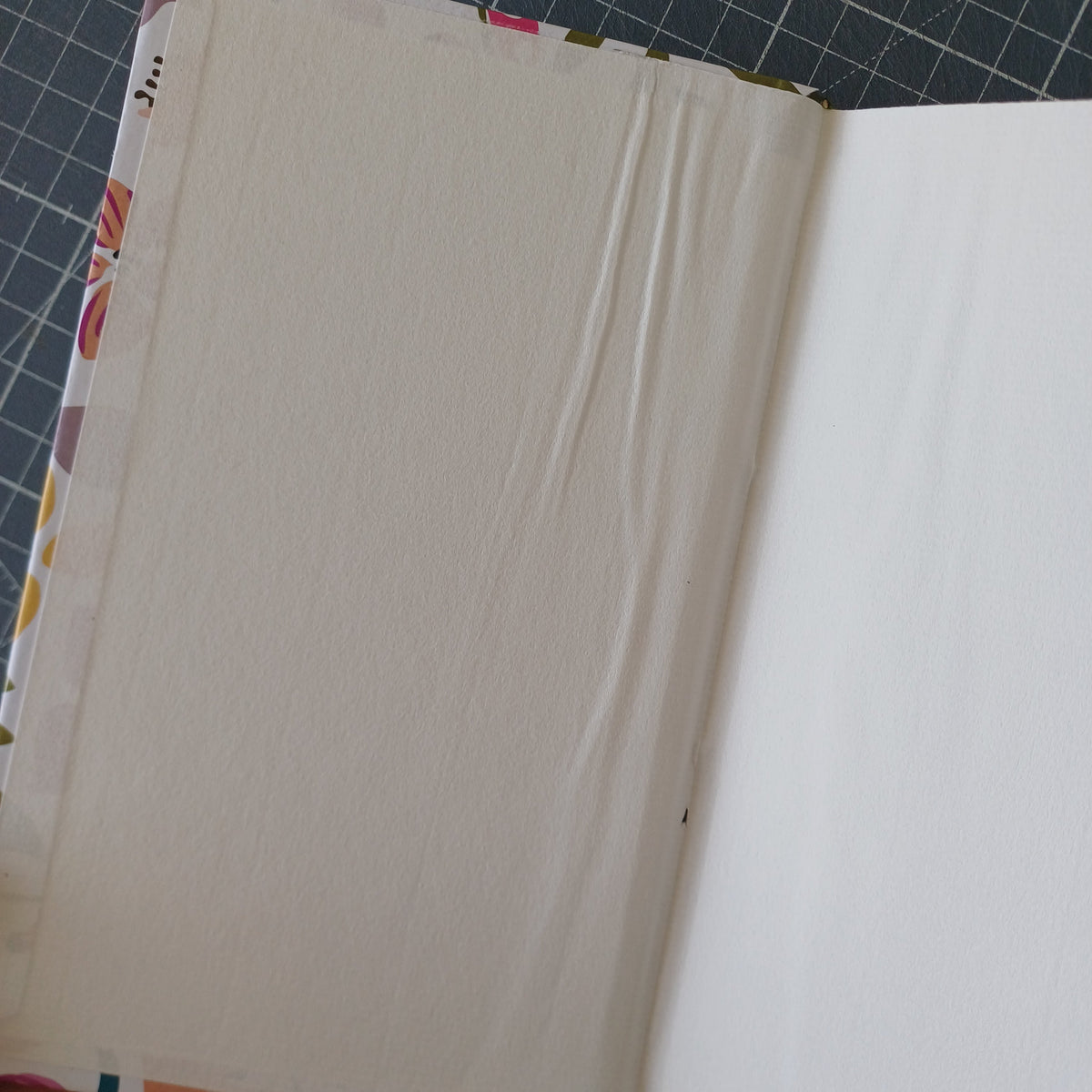 Page de garde blanche d'un carnet artisanal avec des plis dus à un mauvais collage et un petit trou au niveau du pli de la page.