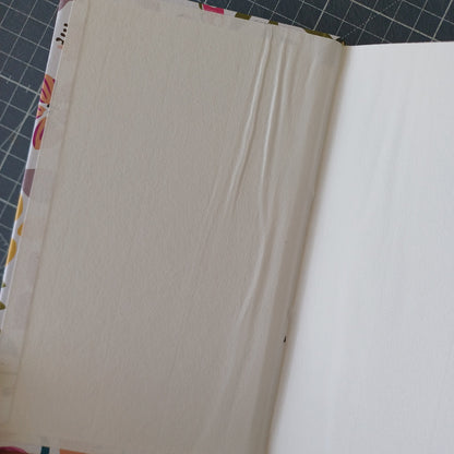 Page de garde blanche d'un carnet artisanal avec des plis dus à un mauvais collage et un petit trou au niveau du pli de la page.
