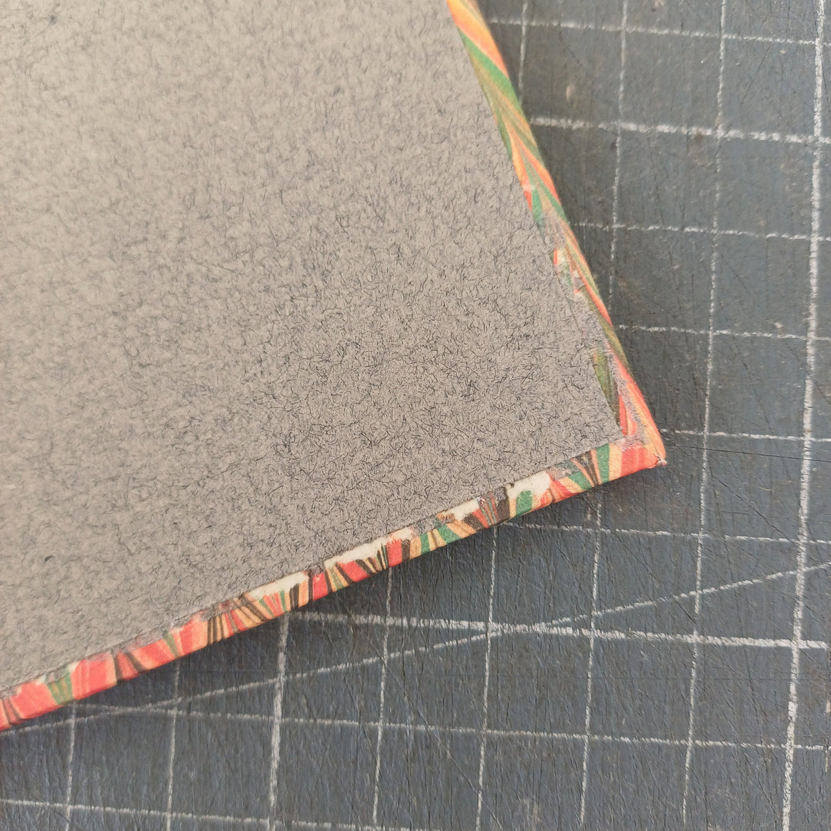 Intérieur d'un carnet artisanal montrant en détail une déchirure du papier au niveau du papier de couverture dans un coin du carnet.