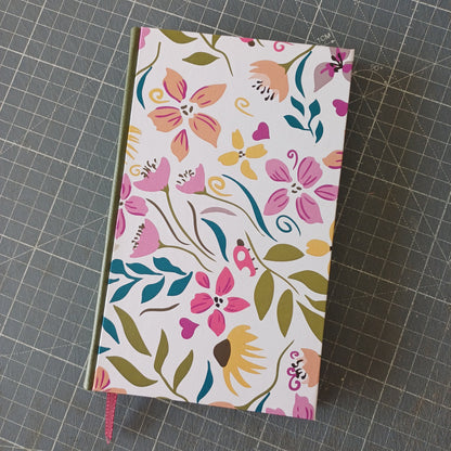 Carnet artisanal à la couverture imprimée de motifs floraux colorés, avec un dos en similicuir kaki et un signet bordeaux.