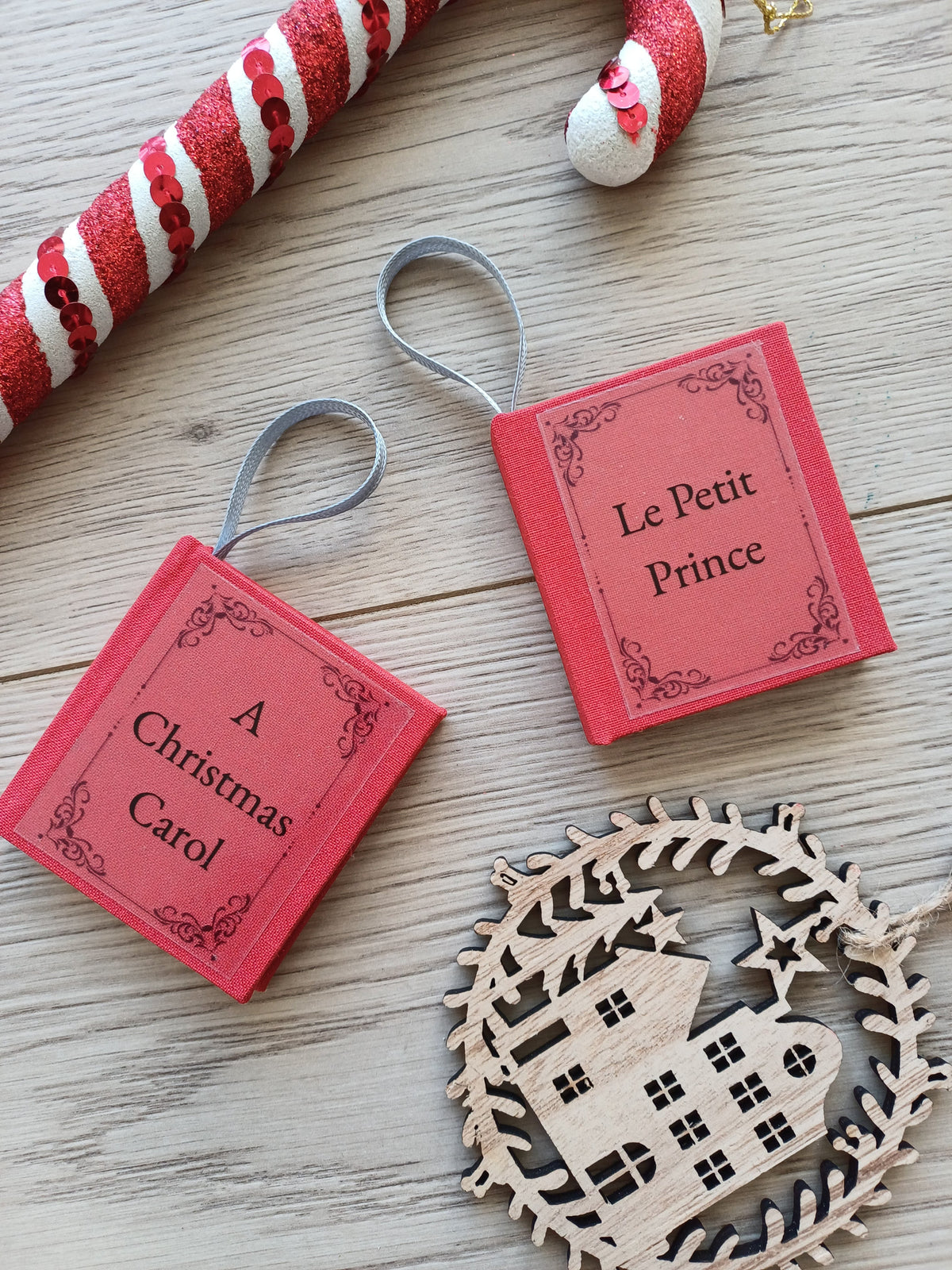 Deux petits carnets rouge en forme de livre aux titres de classiques de la littérature entourés de décorations de Noël.