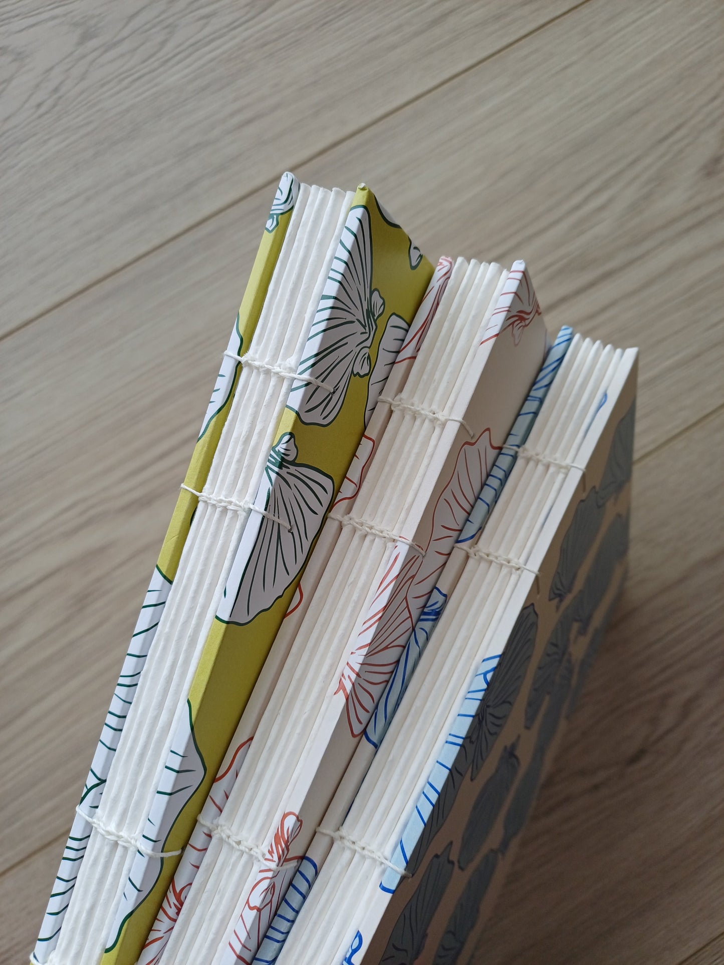 Dos de trois carnets artisanaux pour aquarelle sur lequel on voit la reliure apparente.