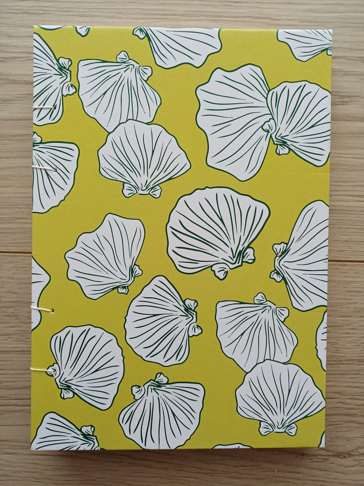 Couverture d'un carnet artisanal pour aquarelle avec des motifs de coquillages sur un fond vert.