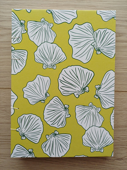 Couverture d'un carnet artisanal pour aquarelle avec des motifs de coquillages sur un fond vert.
